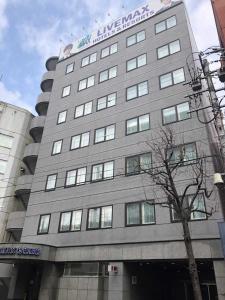 HOTEL LiVEMAX Sapporo Ekimae في سابورو: مبنى رمادي كبير مع وضع علامة عليه