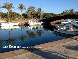 three boats docked in a river with a bridge at Le Dune Bed & Breakfast in SantʼAnna Arresi