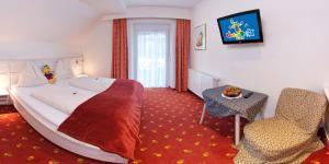 a hotel room with a large bed and a chair at Smileys Kinderhotel in Trebesing
