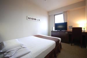 a hotel room with a bed and a desk with a television at Kokusai Hotel Yamaguchi in Yamaguchi