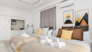 two beds in a living room with white walls at Hotel Apartment Ueno Inaricho Sta in Tokyo