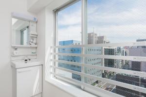 a bathroom with a large window with a sink and a toilet at Ostay UENO Hotel Apartment in Tokyo
