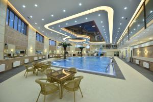 a large pool in a building with tables and chairs at Simma Hotel Spa & Waterpark in Tashkent