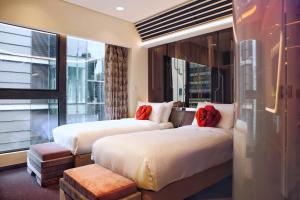 two beds in a hotel room with a window at Butterfly on LKF Boutique Hotel Central in Hong Kong