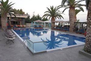 - une grande piscine avec des palmiers dans un complexe dans l'établissement Evvoiki Akti Hotel, à Politiká