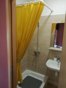 a bathroom with a shower with a yellow shower curtain at City Break Studio Apartment in Zagreb