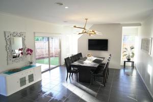 a dining room with a table and chairs and a mirror at Classic 6BRM Villa in Melbourne in Laverton