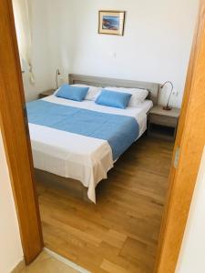 una camera da letto con un grande letto con cuscini blu di Apartments Eva a Malinska