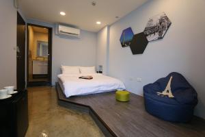 1 dormitorio con 1 cama blanca y 1 silla azul en Lukang Barn Inn en Lugang