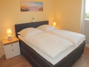 a large bed with white sheets and pillows on it at Strandläufer im Kirschgarten in Kellenhusen