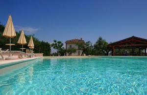 una gran piscina con sillas y sombrillas en Il Casino di Remartello, en Loreto Aprutino