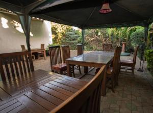 eine Terrasse mit einem Holztisch und Stühlen unter einem Zelt in der Unterkunft Korona House Hotel in Arusha
