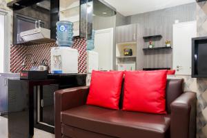 a brown couch with red pillows in a kitchen at Comfy and Clean 2BR Green Pramuka City Apartment By Travelio in Jakarta +7 photos