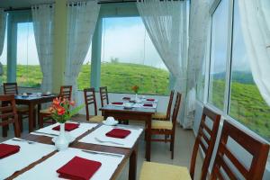 a restaurant with tables and chairs and a large window at Lourdes Hotel in Nuwara Eliya