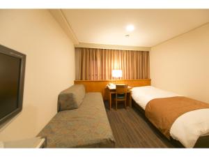 a hotel room with two beds and a television at Hyper-inn Takamatsu Ekimae in Takamatsu