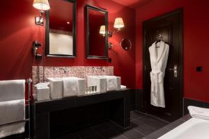 a bathroom with red walls and a white robe on a rack at Hotel Des Indes The Hague in The Hague