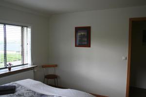 a bedroom with a bed and a window and a chair at Guesthouse Svinavatn in Svínavatn