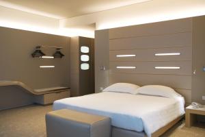 a bedroom with a large white bed and a stool at Best Western Plus Net Tower Hotel Padova in Padova