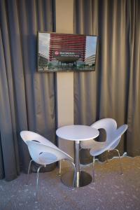 two white chairs and a table and a tv at Best Western Plus Net Tower Hotel Padova in Padova