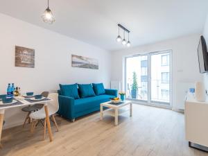 a living room with a blue couch and a table at Bodnar Apartamenty Nadmorskie Tarasy Port in Kołobrzeg