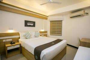 a bedroom with a bed and a desk and a bed sidx sidx sidx at Sapphire Club Metro in Ernakulam