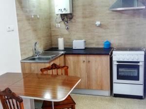 a kitchen with a table and a sink and a stove at Vivenda Palheiras in Roncão
