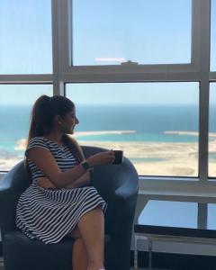 a woman sitting in a chair looking out a window at S Hotel Bahrain in Manama