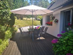 a patio with a table and chairs and an umbrella at Joelle et Hans B&B in Hôpital-Camfrout
