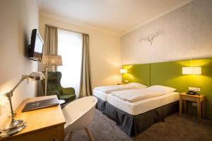 a hotel room with a bed and a desk at Hotel Deutschherrenhof in Zeltingen-Rachtig