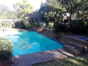 a swimming pool in a yard with a brick wall at Fourways Guest Lodge in Johannesburg
