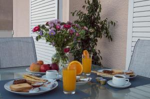 - une table avec des aliments pour le petit-déjeuner, du jus d'orange et des fleurs dans l'établissement Elegance in Athens, à Athènes