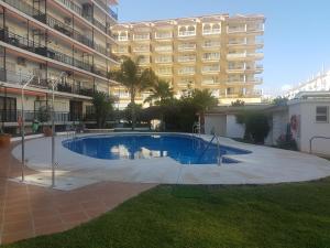 a swimming pool in front of a large building at Cosy flat near the beach & town centre in Fuengirola