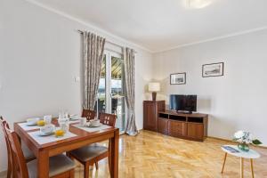 a dining room with a table and chairs and a television at Apartman Ivan in Malinska