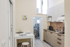 una piccola cucina con armadi bianchi e un tavolino di Bari Centrale Railway Station Apartment a Bari