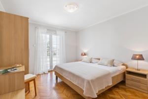 a white bedroom with a bed and a window at Apartman Ivan in Malinska