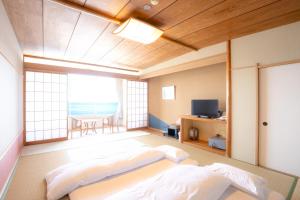 a large room with two beds and a television at Kameya Rakan in Ito