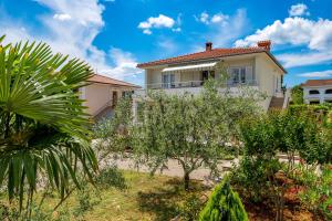 a white house with trees in front of it at Apartman Ivan in Malinska