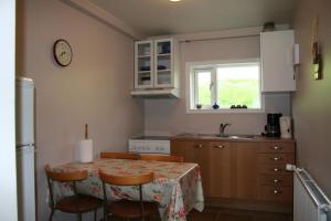 a kitchen with a table with chairs and a window at Guesthouse Svinavatn in Svínavatn