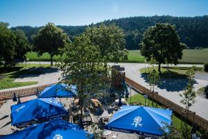 eine Luftansicht eines Resorts mit blauen Sonnenschirmen in der Unterkunft Hotel Räucherhansl in Loiching