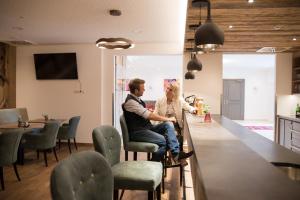 a man and woman sitting at a bar in a room at Hotel Räucherhansl in Loiching