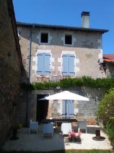 a table with an umbrella in front of a building at La Poste Saulgond in Saulgond