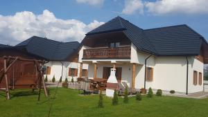 a house with two black roofs and a yard at Apartamenty Białowieża in Białowieża