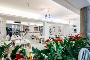 un restaurante con mesas, sillas y plantas en Hotel Palace, en Lignano Sabbiadoro