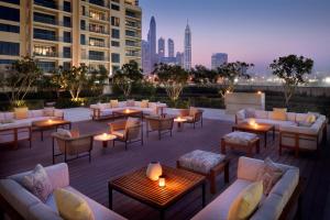 a rooftop patio with couches and tables with a city skyline at Vida Emirates Hills in Dubai