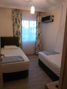 two beds in a small room with a window at GÜMÜLDÜR ÇALIŞKAN APART 1 in Gumuldur