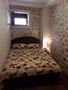 ein Schlafzimmer mit einem Bett mit einer Bettdecke und einem Fenster in der Unterkunft Apartments Ana in Kotor
