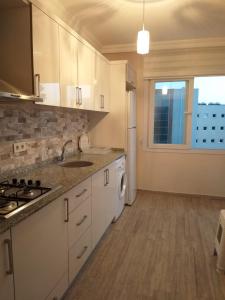 a kitchen with white cabinets and a sink and a window at GÜMÜLDÜR ÇALIŞKAN APART 1 in Gumuldur