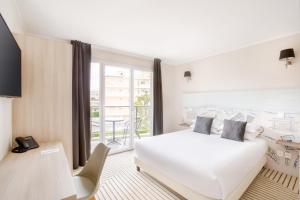アンティーブにあるベスト ウエスタン プラス アンティーブ リヴィエラの白いベッドとバルコニーが備わるホテルルームです。