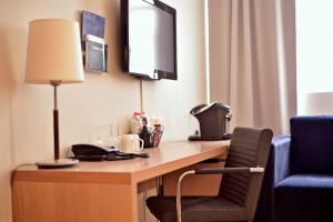 a desk in a hotel room with a television and a chair at Clarion Collection Hotel Savoy in Oslo