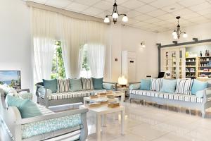 a living room with blue and white couches and tables at Acrotel Elea Beach in Elia